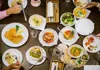 Overhead view of assorted Austrian dishes including schnitzel, potato salad, tomatoes, and sides on a restaurant table