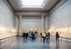 A picture of tourists looking at the Parthenon Sculptures inside of the British Museum in London.