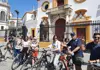 Participants on a guided bike tour posing with their bicycles outside Seville’s Plaza de Toros bullring.