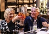 A person and person holding glasses of drinks and cheering