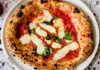 Neapolitan Margherita pizza with blistered crust, tomato sauce, mozzarella, and basil leaves.