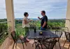 Two guests tasting white wine on a terrace overlooking vineyards and countryside