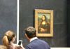 A couple looking at the Mona Lisa while visiting the Louvre Museum.