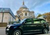 A traditional London Black Cab parked in front of St. Paul's Cathedral.