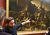 A tour guide next to the Raft of Medusa in the Louvre Museum.