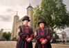 A group of tourists taking a picture with a Tower of London Beefeater.