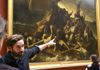 A tour guide in the Louvre Museum speaking about the Raft of Medusa to a group on tour with The Tour Guy.