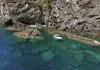 Small boat anchored in a narrow cove with clear turquoise water and rocky cliffs in Cinque Terre.