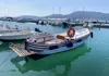 Classic wooden boat moored in a marina with other boats and hills in the background