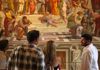A group of tourists looking at the School of Athens with their guide from The Tour Guy.