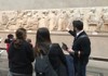 A picture of a guide showing artwork inside of the British Museum to tourists in London.