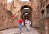 A couple walks through an ancient stone archway inside the Colosseum, exploring the underground passage.