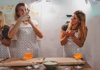 Two women in aprons making food and taking pictures