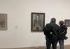 A couple looking at a wall of art in the Tate Modern in London.