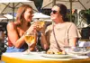Two women sitting at a restaurant in Paris with wine and escargot.