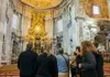Tour group gathered inside St. Peter’s Basilica, facing Bernini’s bronze baldachin and the papal altar