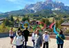 Visitors walking near the Olympic rings with alpine mountains and village scenery in the background