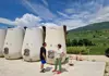 Guide speaking with guests beside large modern wine fermentation tanks at a winery
