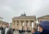 Visitors gathered near the Brandenburg Gate on a cloudy day during a guided tour