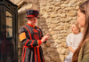 A pair of tourists speaking with  a Tower of London Beefeater