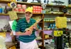 Local shopkeeper holding a cured pork leg inside a traditional Italian deli