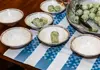 Chef serving freshly made gnocchi to guests seated at a table during a cooking class