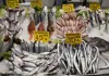 Fish market display with rows of fresh seafood on ice and handwritten price signs
