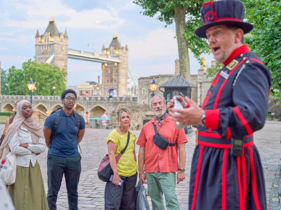 Two tourists taking a picture with a Tower of London Beefeater while on tour with The Tour Guy.