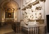 A sculpted marble monument featuring dramatic figures in a dynamic composition, set within a grand museum hall.