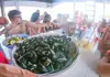 Passengers dining together on a boat while a large bowl of fresh mussels is served.