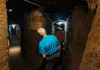 a tourist going around the Domitillas Catacombs hallways in Rome