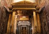 A richly decorated church entrance with golden embellishments, flanked by marble columns and religious iconography.