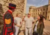 A group of tourists taking a picture with a Tower of London Beefeater.