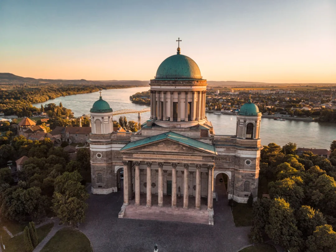 Aerial view of Esztergom Basilica at sunrise with the Danube River flowing behind it.