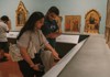 A museum curator carefully turns the pages of an ancient manuscript in a dimly lit research space.