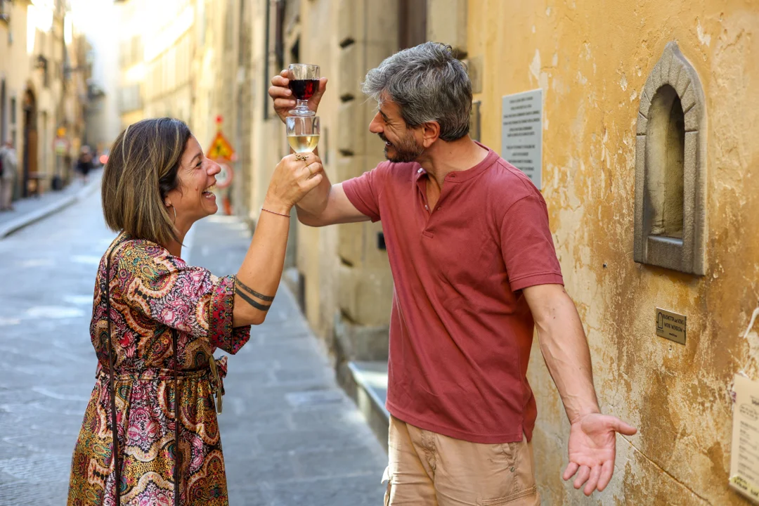 Guest receiving a glass of wine through a historic wine window set into a stone wall