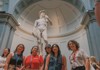 A group of tourists having their picture taken in front of the Statue of David while on tour with The Tour Guy.